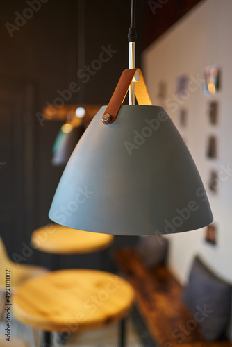 gray lamp on a loft-style leather strap in an empty coffee shop with round wooden tables photo