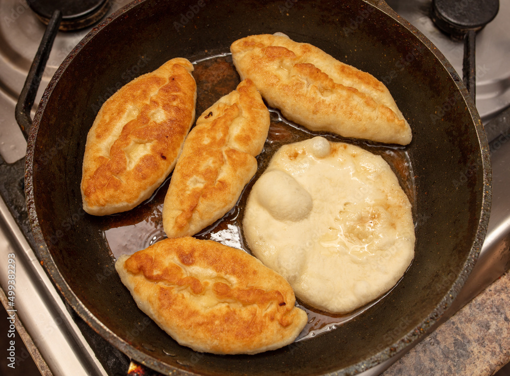 Pies are fried in oil in a frying pan. Pies are fried in oil in a frying pan.
