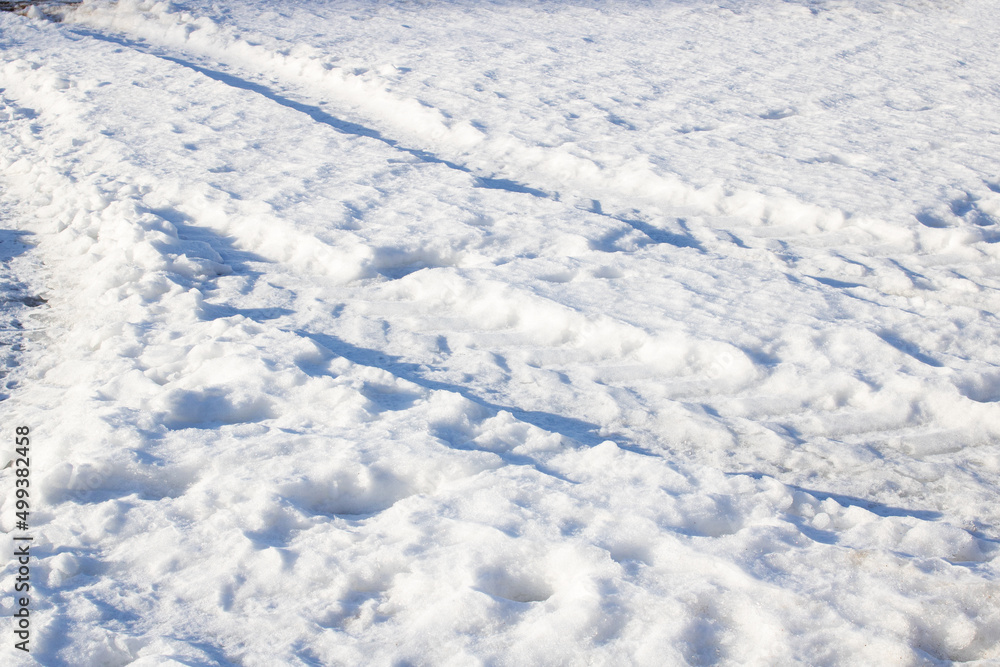 Car tracks in the snow in sunlight