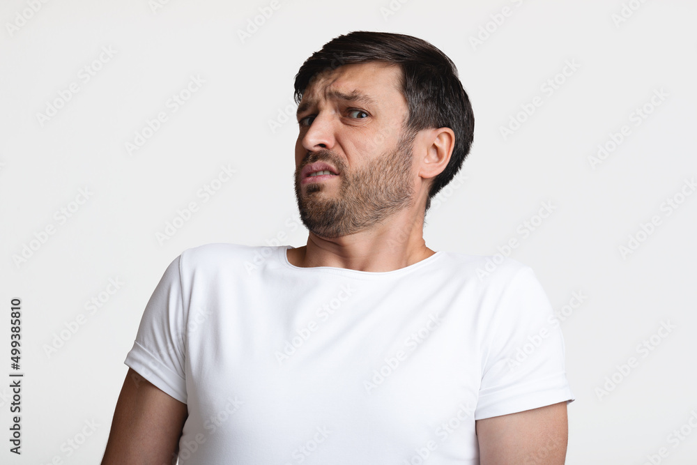 Disgusted Man Smelling Unpleasant Odor Expressing Negative Emotions, White Background Disgusted Man Smelling Unpleasant Odor Expressing Negative Emotions, White Background