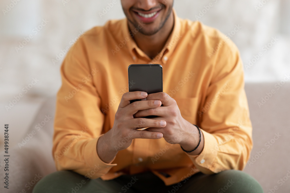 Smiling young man using smartphone at home, close up Smiling young man using smartphone at home, close up