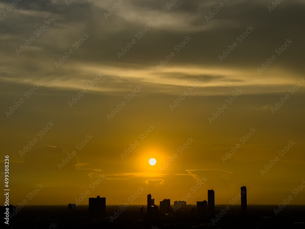 Silhouette of City skyline at dawn, yellow and golden of sunrise or sunset Selective focus Sunrise or sunset over a local office building in Bangkok's business of high building