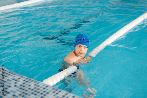 A little boy of eight years old is learning to swim in a modern swimming pool. Development of children's sports. Healthy parenting and promotion of children's sports.