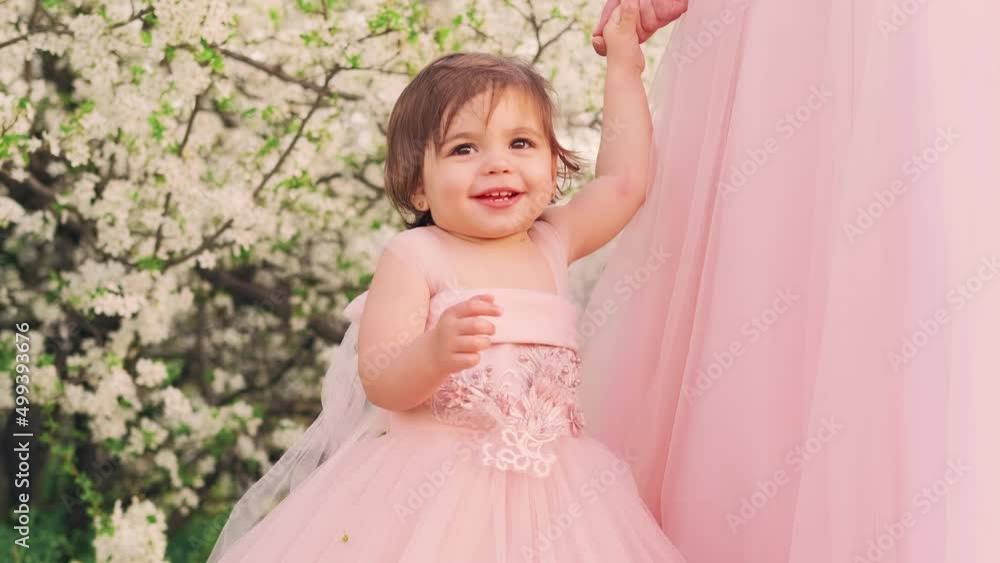 Portrait Little happy, beautiful, joyful, cheerful girl in a luxurious fluffy pink dress. Child princess smiling face vintage ball gown style. Background spring nature flowering white tree green grass Portrait Little happy, beautiful, joyful, cheerful girl in a luxurious fluffy pink dress. Child princess smiling face vintage ball gown style. Background spring nature flowering white tree green grass