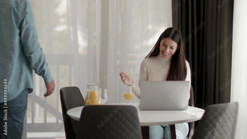Young couple using laptop computer on the table in the living room and drinking orange juice