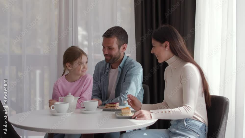 Happy young family eat cakes and drink tea together in the room Happy young family eat cakes and drink tea together in the room