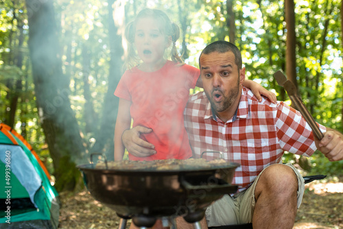 Father and daughter making barbecue in the nature. Family camping concept