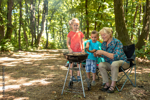 Family picnic concept with grandchildren and grandmother making barbecue