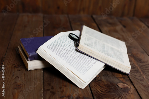 Stack of antique books with magnifying glass on wooden table