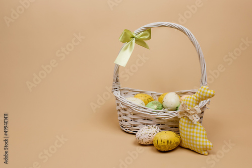 Colorful Easter eggs in a basket on a beige background.