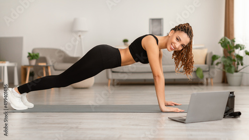 Fit Black Woman Near Laptop Standing In Plank At Home