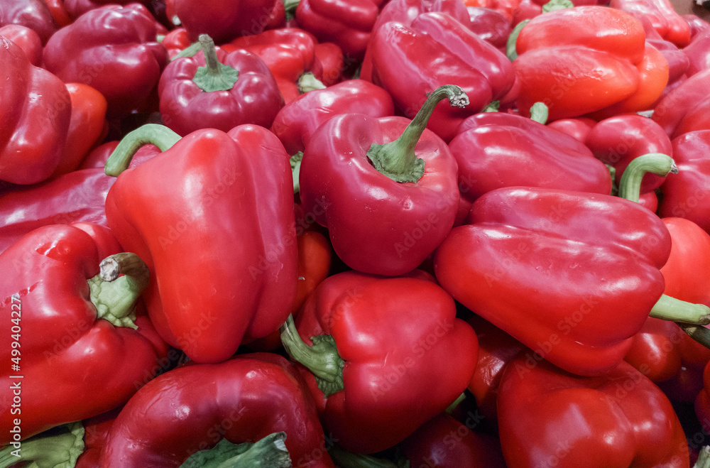 Red bell peppers on a counter in the supermarket. A large number of red peppers in a pile. Assortment of shops and market. Background. View from above. Vegetables. Agriculture Red bell peppers on a counter in the supermarket. A large number of red peppers in a pile. Assortment of shops and market. Background. View from above. Vegetables. Agriculture