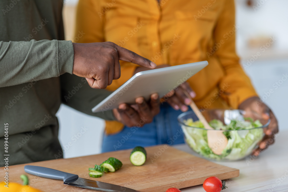 Obraz premium Black Man And Woman Using Digital Tablet While Cooking Lunch In Kitchen