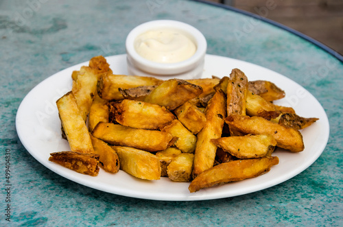 Home-made fries on a plate with some mayonaise on a round table