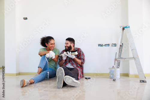 Obraz na plátně Portrait Cheerful couple young man and black woman smiling during renovation in