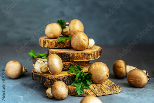 Raw mushrooms champignons with parsley on grey background