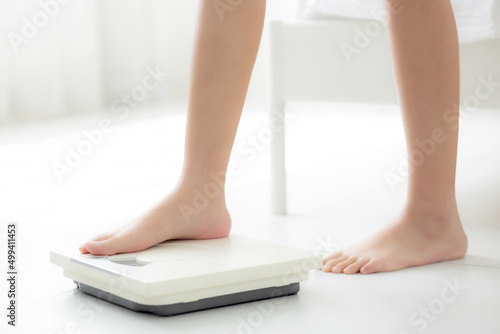 Closeup foot of woman standing on scales measuring for control weight in the room, overweight and dieting, health and weightloss, examining fat with weighing, indoor, healthy concepts.