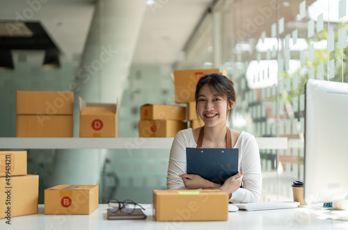 Portrait young attractive asia female owner startup look at camera work happy with box at home prepare parcel delivery in sme supply chain, procurement, omnichannel ecommerce online concept