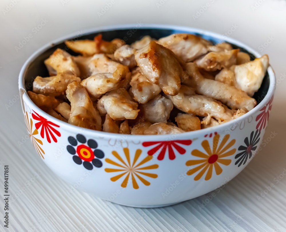 Pieces of fried chicken in a ceramic cup close-up on the background of a light kitchen table Pieces of fried chicken in a ceramic cup close-up on the background of a light kitchen table