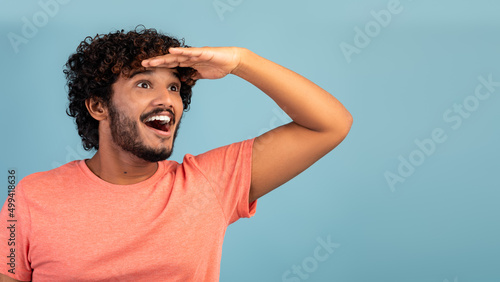 Excited hindu guy looking at copy space on blue