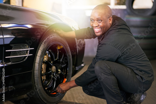 Professional service with a smile. Cropped shot of a mechanic repairing a car tyre. © Nola V/peopleimages.com
