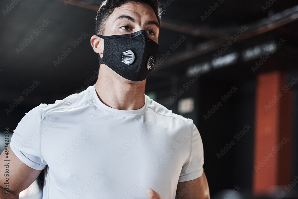 Working out and staying safe. Cropped shot of a handsome and athletic young man wearing a mask while working out in the gym. Working out and staying safe. Cropped shot of a handsome and athletic young man wearing a mask while working out in the gym.