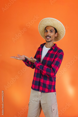 Junina Party. Black Man With Outfit Pointing Isolated on Orange Background.