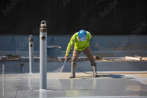 Top view male worker holding an industrial spray gun used for roof plate tank surface on steel industrial painting