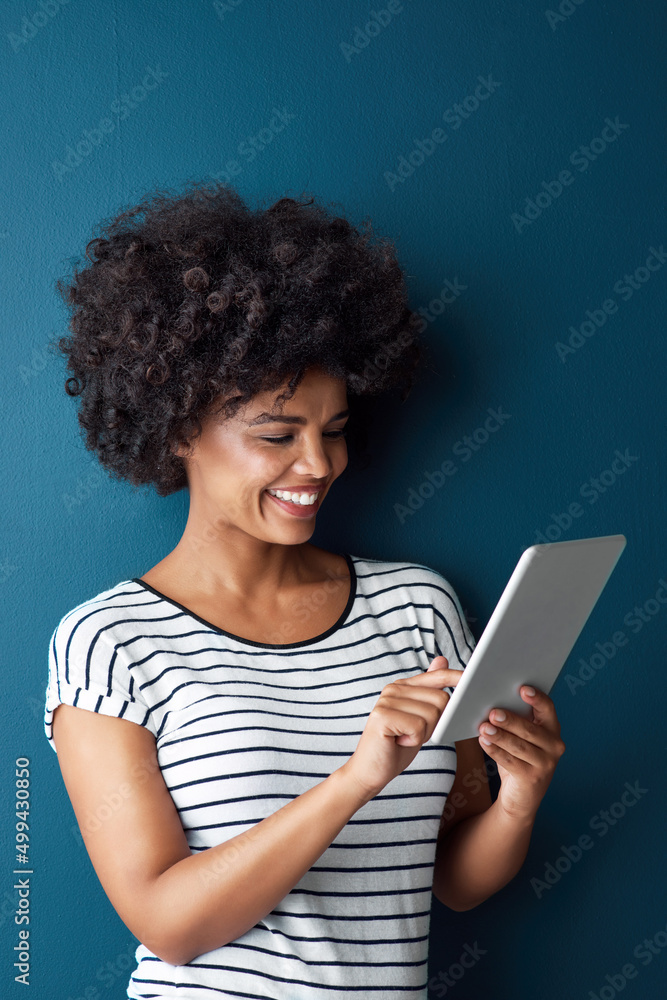 Diving right in to the digital world. Studio shot of an attractive young woman using a digital tablet against a blue background. Diving right in to the digital world. Studio shot of an attractive young woman using a digital tablet against a blue background.