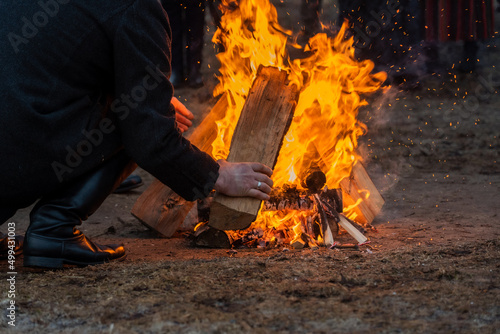 A man's hand with a log and a fire.