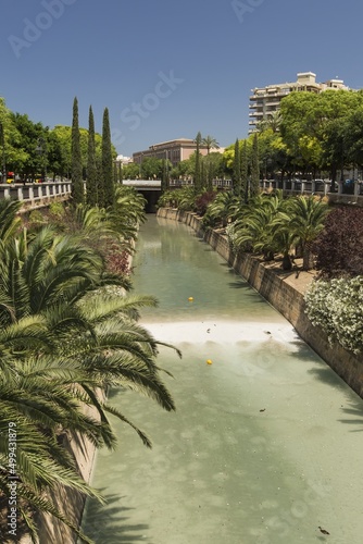 View of a canal of water crossing a park in the Historic Center of Palma de Mallorca, Balearic Islands, Spain. Tourist places, beautiful sunny day.