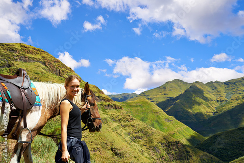 On top of the world. A young woman with her horse on a mountain trek.