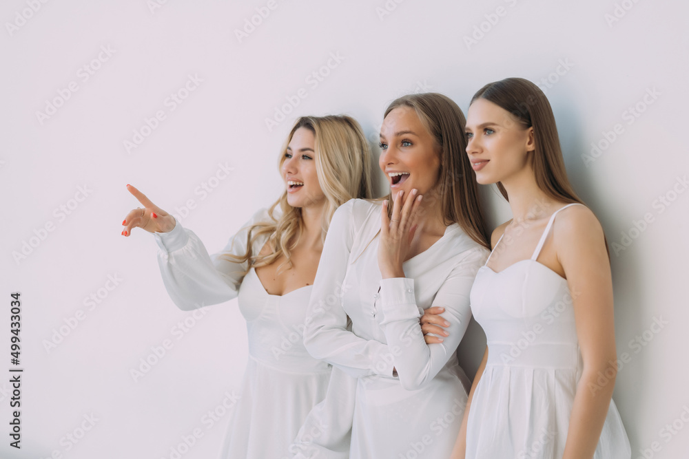 Pleased three women smiling pointed side over white background Pleased three women smiling pointed side over white background