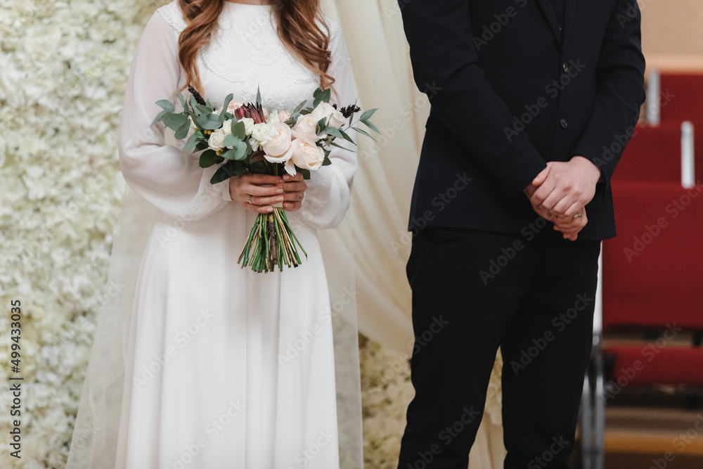 wedding day. bride in long white dress with bouquet of flowers and groom in black suit on wedding ceremony wedding day. bride in long white dress with bouquet of flowers and groom in black suit on wedding ceremony