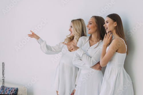 Pleased three women smiling pointed side over white background