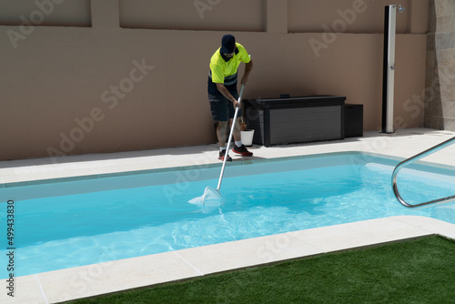 Operator cleaning a swimming pool with a butterfly trap