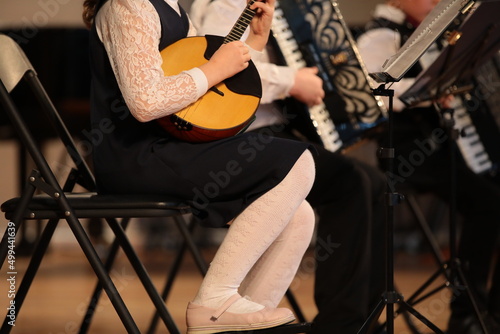 A student girl plays the balalaika in an ensemble of musicians in a lesson at school photo