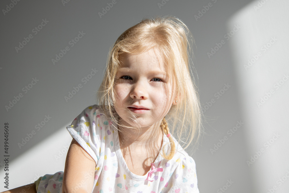 Sad child girl blonde with disheveled hair on the background of a white wall. Sad child girl blonde with disheveled hair on the background of a white wall.
