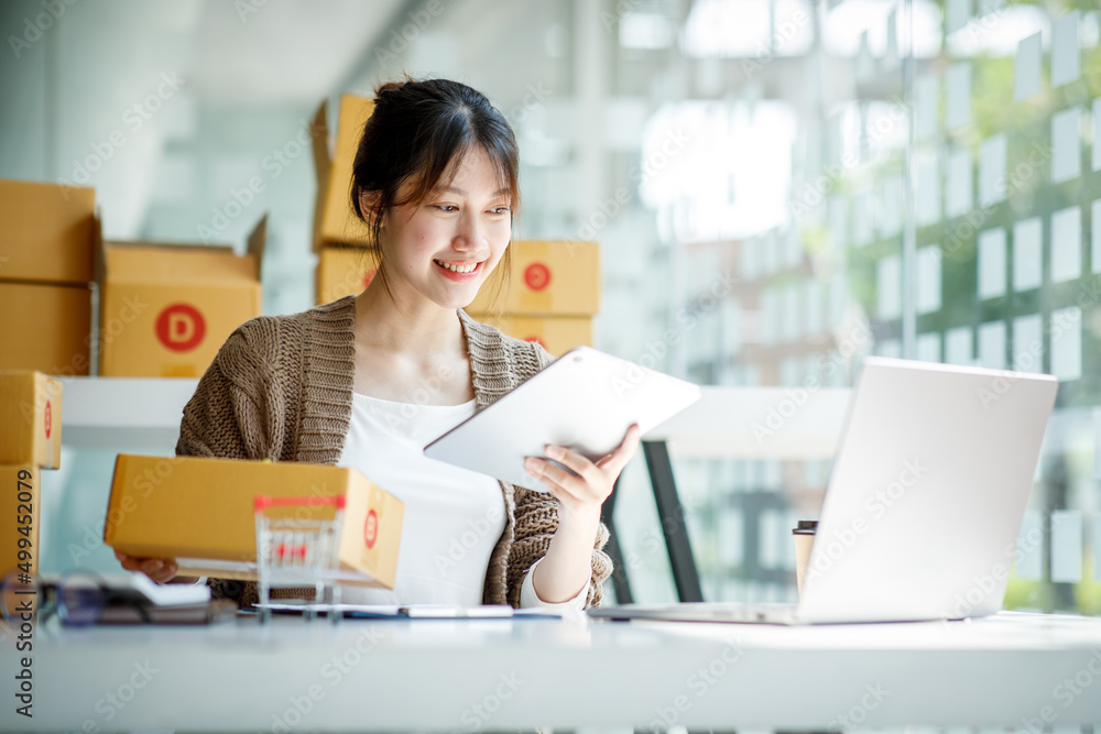 Startup small business entrepreneur SME or freelance Young Asian woman using a laptop computer with box, successful Asian woman working, online marketing packaging delivery, SME online business ideas. Startup small business entrepreneur SME or freelance Young Asian woman using a laptop computer with box, successful Asian woman working, online marketing packaging delivery, SME online business ideas.