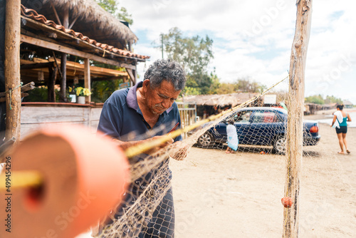 Elderly fisherman repairing a cast net used to fish for squid on a Nicaraguan beach. Lifestyle of indigenous communities of Central America.