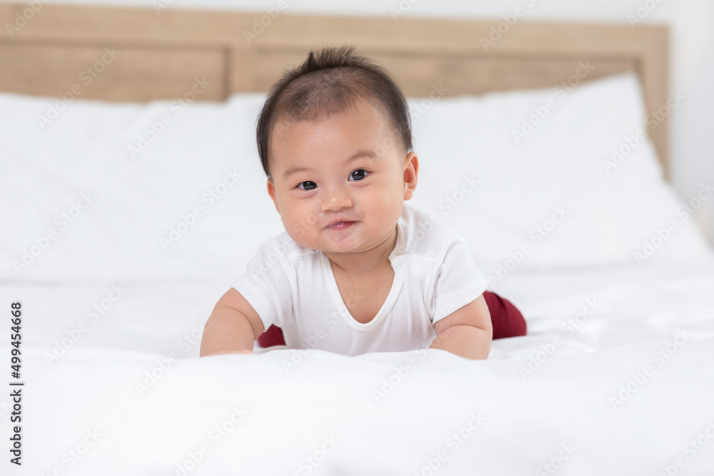 Happy Newborn baby laying on stomach developing neck control .tummy time for strengthen baby neck and shoulder muscles.Cute infant lying crawling on white bed happiness and fun.Tummy Time Concept Happy Newborn baby laying on stomach developing neck control .tummy time for strengthen baby neck and shoulder muscles.Cute infant lying crawling on white bed happiness and fun.Tummy Time Concept
