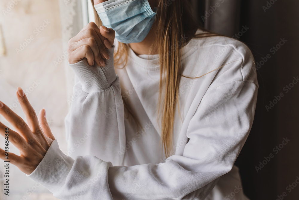 woman near the window in the medical mask and coughing. Self isolation and quarantine woman near the window in the medical mask and coughing. Self isolation and quarantine