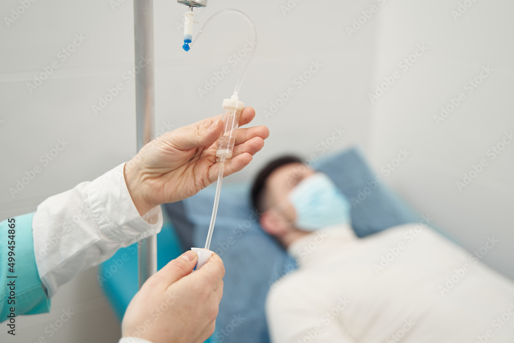 Woman fixing drip for ill man on couch Woman fixing drip for ill man on couch