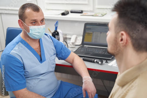 Male practitioner in mask during consultation with patient