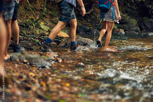 The only thing better than exploring is exploring with friends. Cropped shot of a group of unidentifiable hikers crossing a stream while exploring in the woods. © K Seisa/peopleimages.com