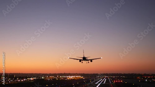 Airport runway lights at night, plane or airplane landing to airstrip, twilight dusk and sunset. Airliner jet arriving to aerodrome, San Diego airfield, California USA. Aircraft flying mid air in sky.
