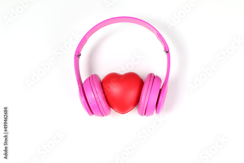 pink headphones with red heart sign in the middle on white surface.