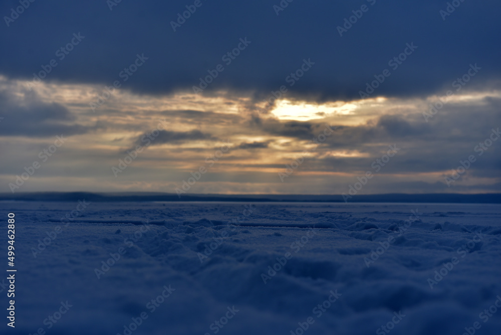 sunset over the snow-covered surface of the lake