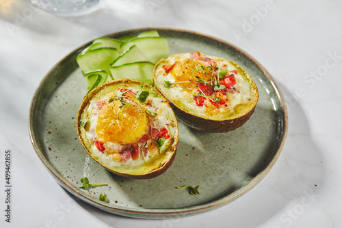 Avocado baked with egg, ham, tomatoes and cheese. Keto lunch recipe. After baking