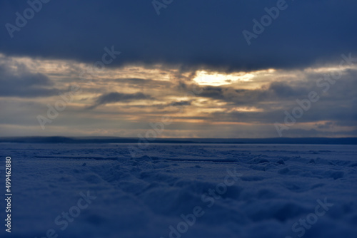 sunset over the snow-covered surface of the lake